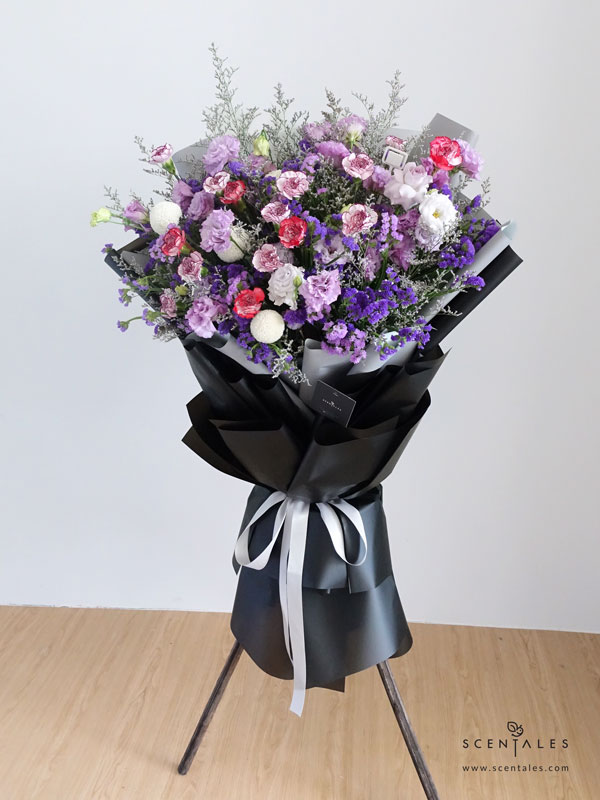 Alice’s Dream Opening Flower Stand Fresh flower stand Purple eustoma (or rose), purple carnation, white carnation, white ping pong, plenty of purple statice and caspia